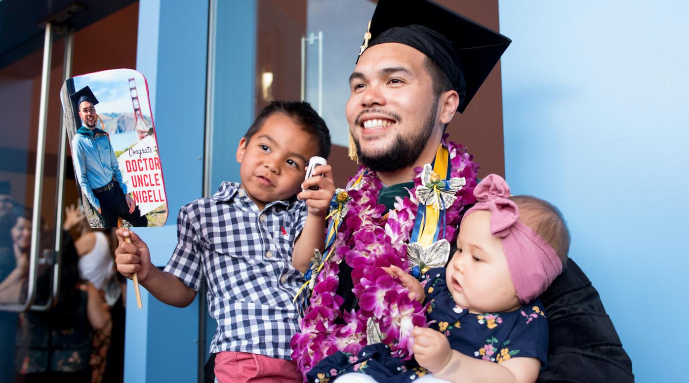 UCSF graduate poses for a photo holding two children