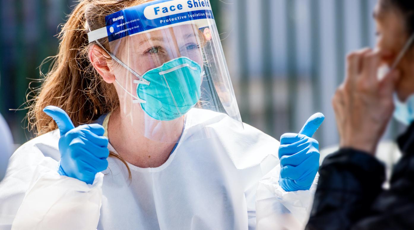 Nurse in PPE gives a patient two thumbs up 