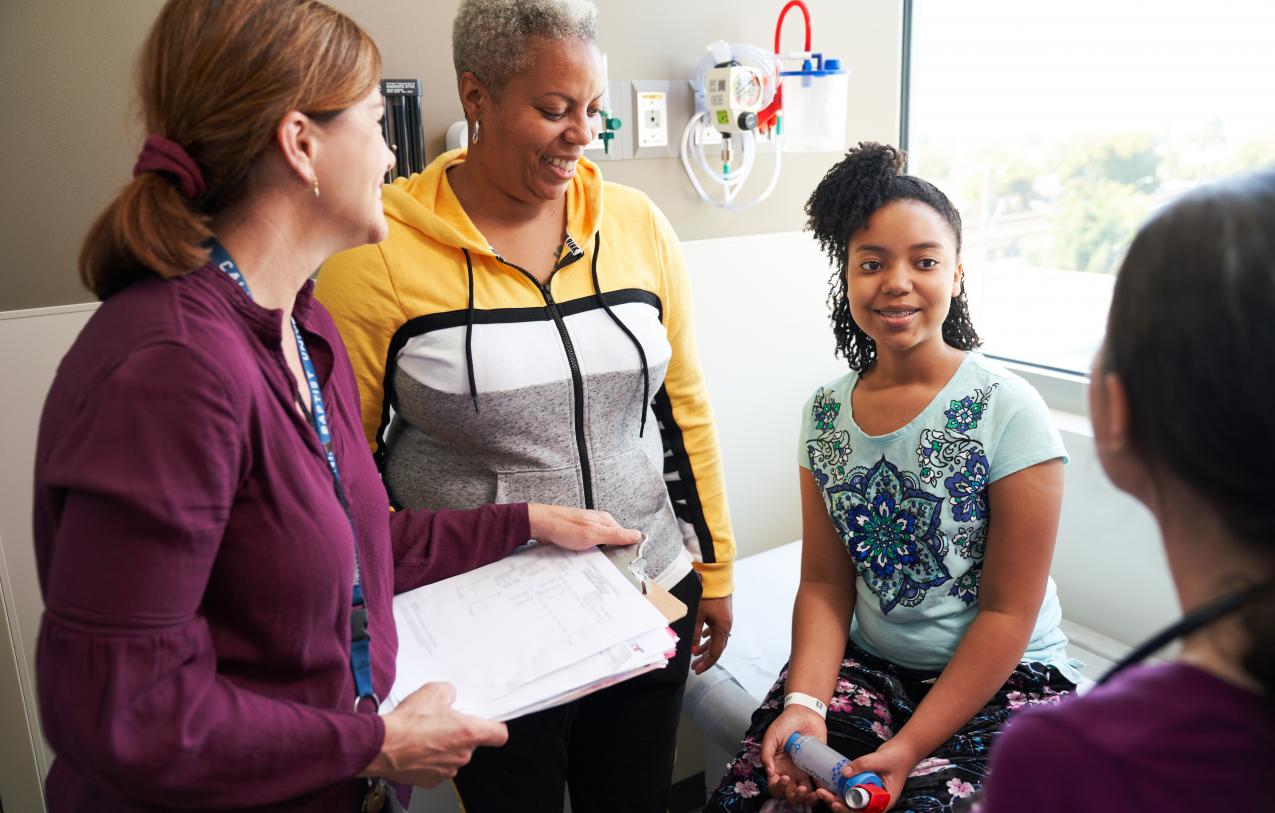 Child with asthma sits with physician 