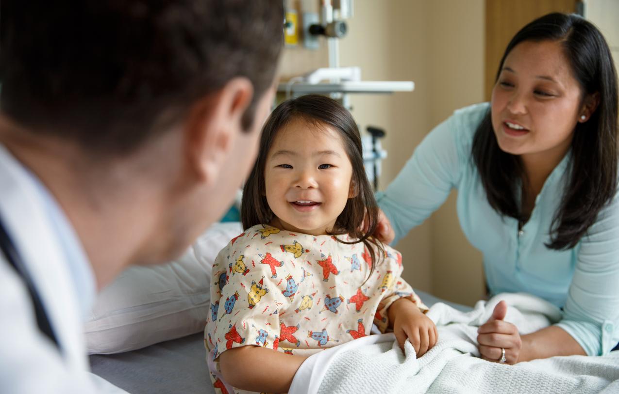 Child in a hospital bed sits with mother