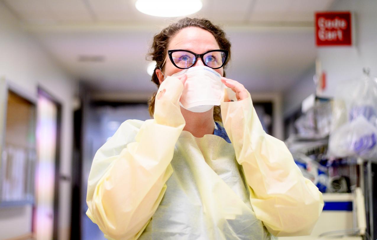 Nurse in PPE puts on a face mask