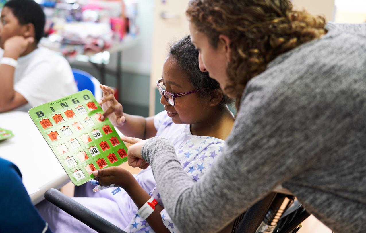 A Young girl playing bingo with another woman