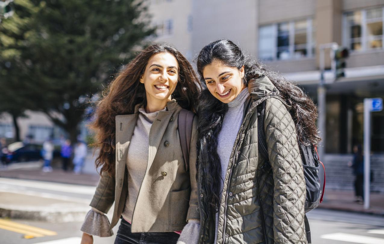 two women smiling and walking across campus 