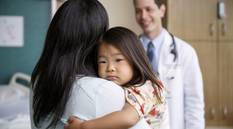 Mother holds child while talking to doctor 