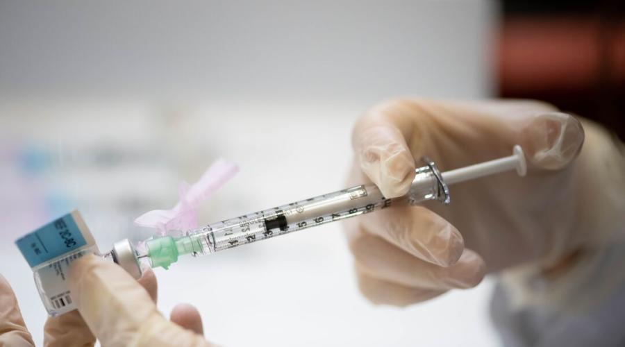 A vaccination needle pulls from a vial.