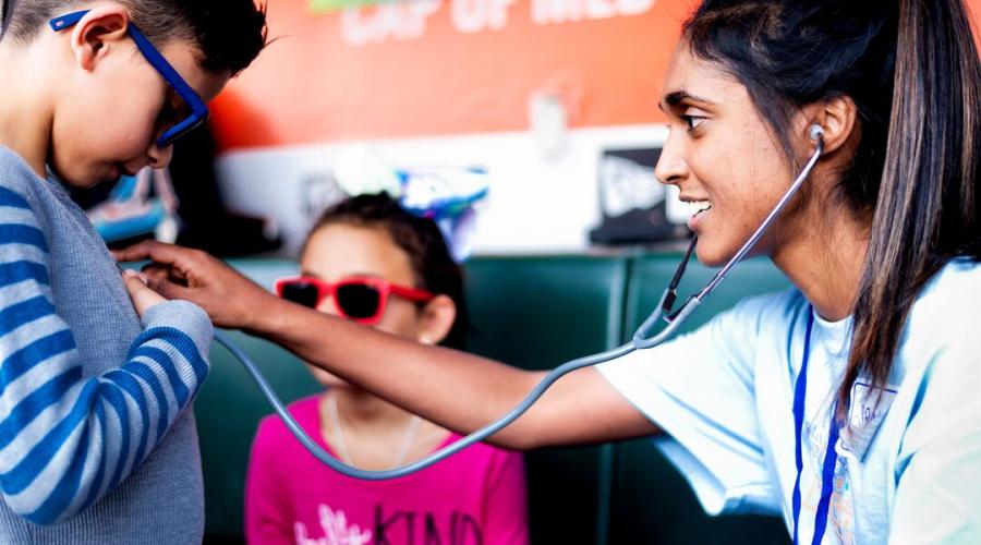 A nurse uses a stethoscope on a young patient