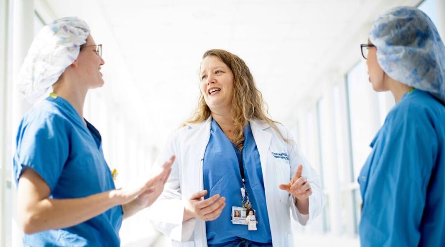 Three physicians talk in a hospital hallway
