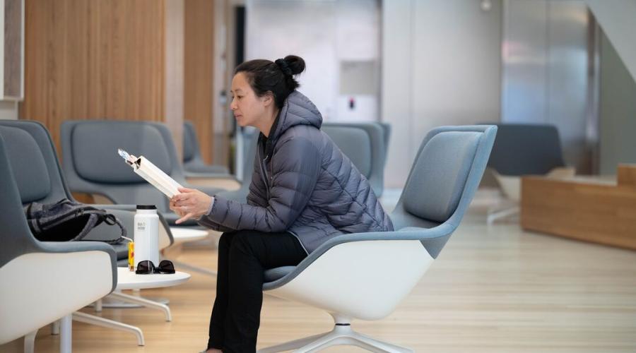 A woman reads a pamphlet in a hospital lobby