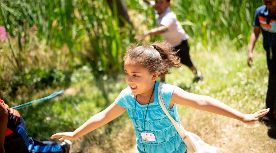 A young girl runs in the woods with friends