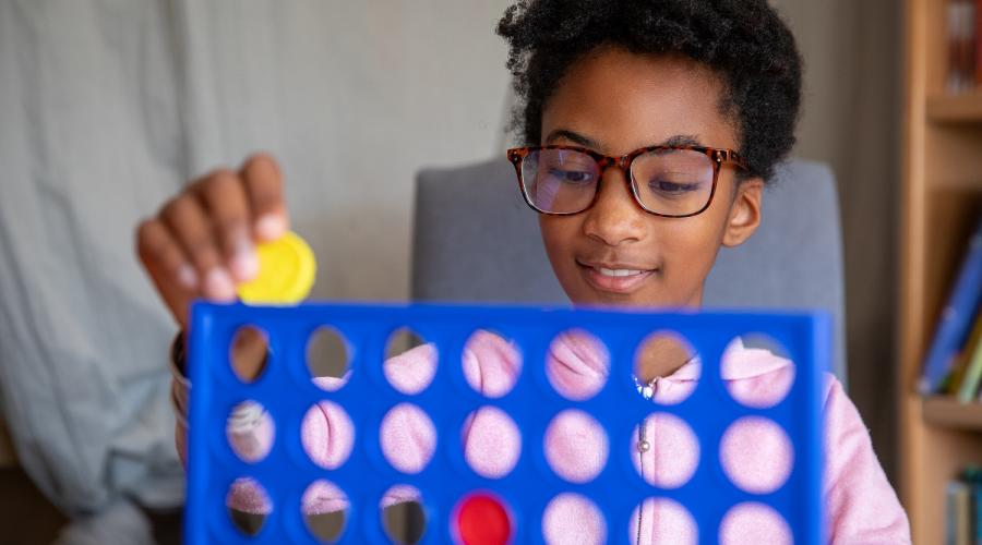 A young child plays Connect 4