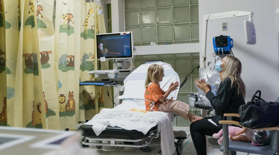 A physician and a child laugh in an exam room