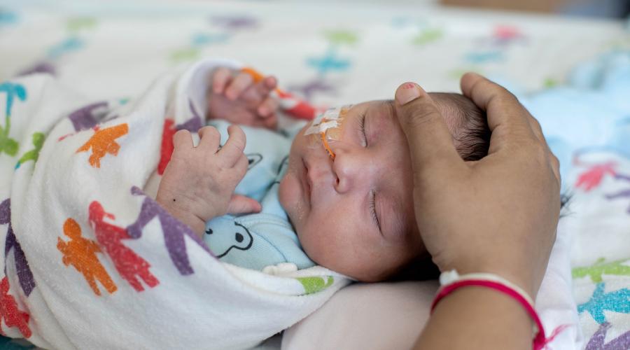 An infant is soothed by a hand on its head
