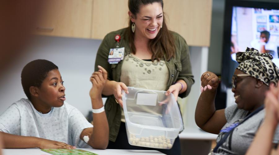 From left to right, patient Marc; Katie Craft, CLS; and Marc's mother, Clarice, playing BINGO in the teen lounge playroom at UCSF Benioff Children's Hospital Oakland. Photo by Steve Babuljak.