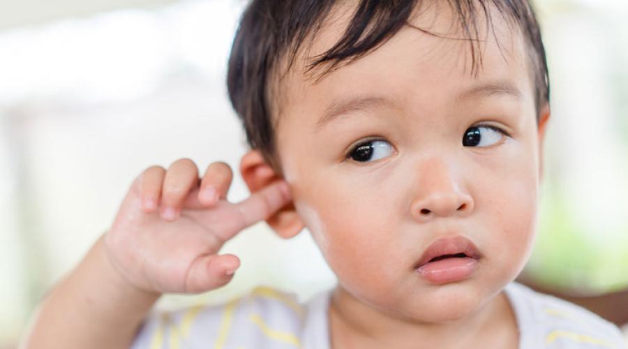 A child fusses with their ear. 